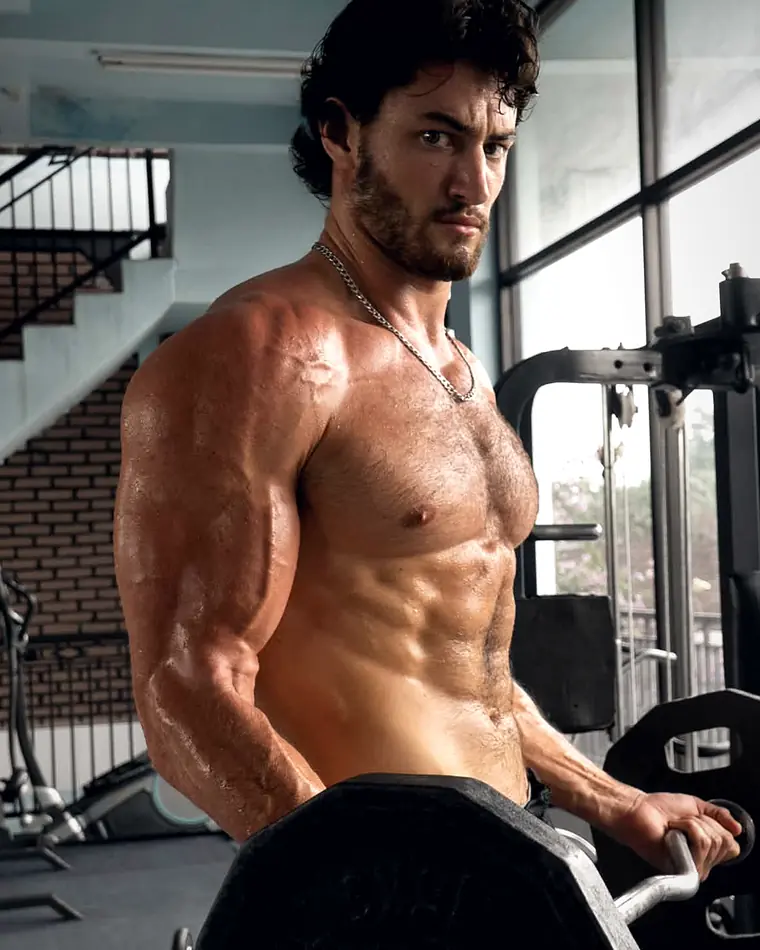 Matthew Heim holding a loaded EZ bar beside the gym window